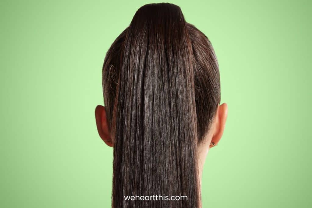 a close-up image of a woman facing backward highlighting her black straight ponytail hair extentions
