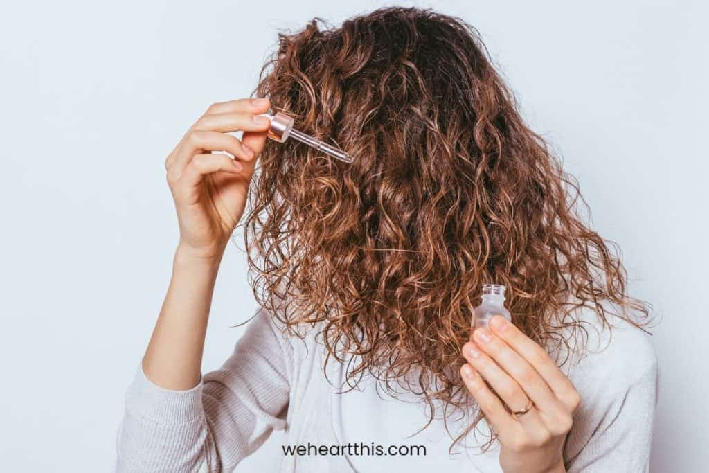 a young girl with low porosity hair is applying oils on her hair strands for pre poo