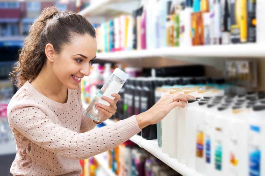 A woman is choosing a shampoo in a store.