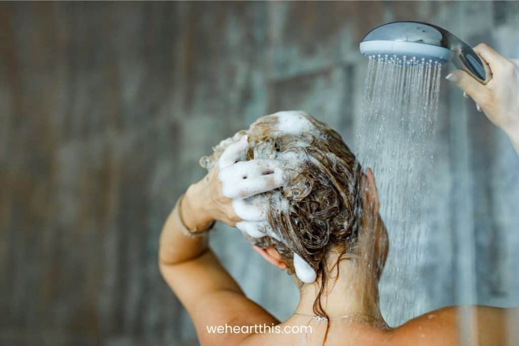 Back of a woman taking a shower and using shampoo
