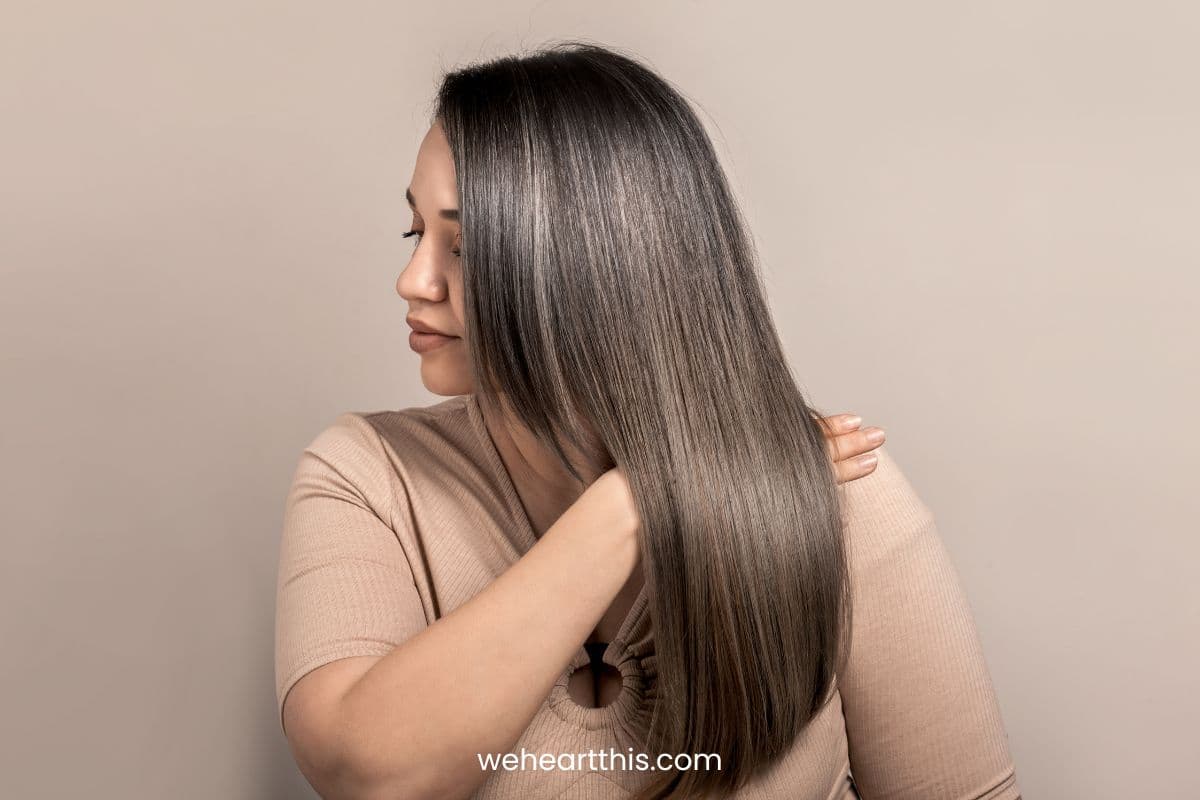 a woman flaunting her long shiny hair with gray highlights
