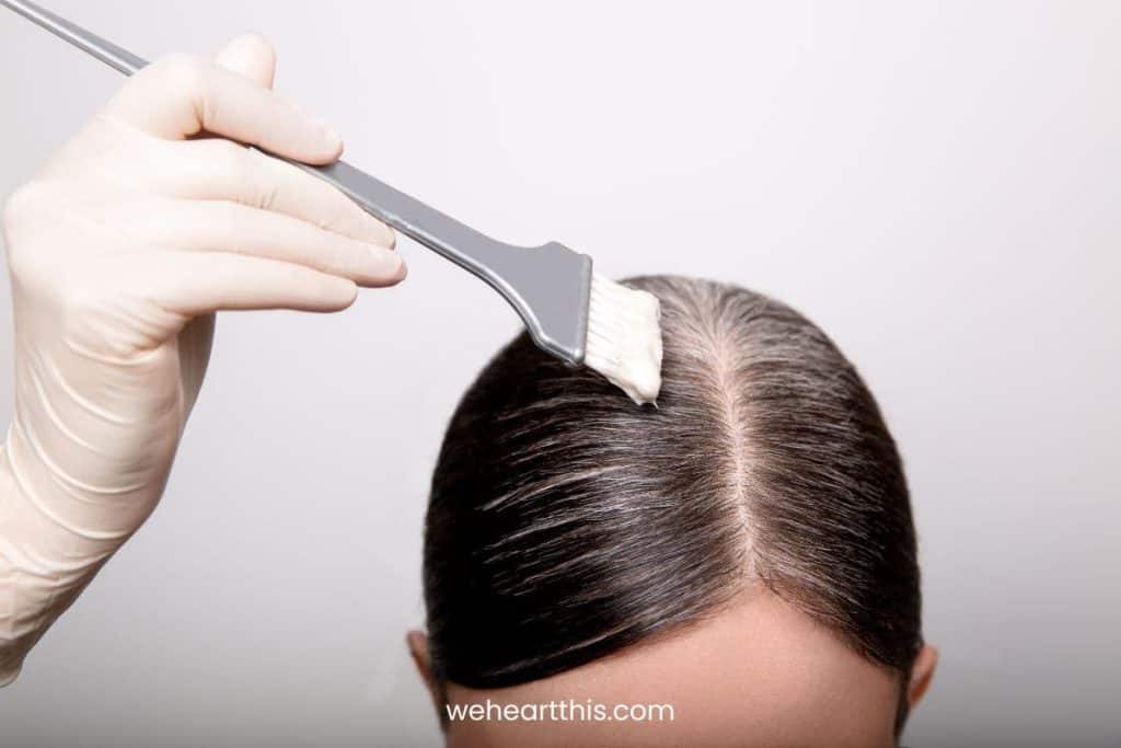 a woman applying her own hair color using a gray brush for gray blending for dark hair