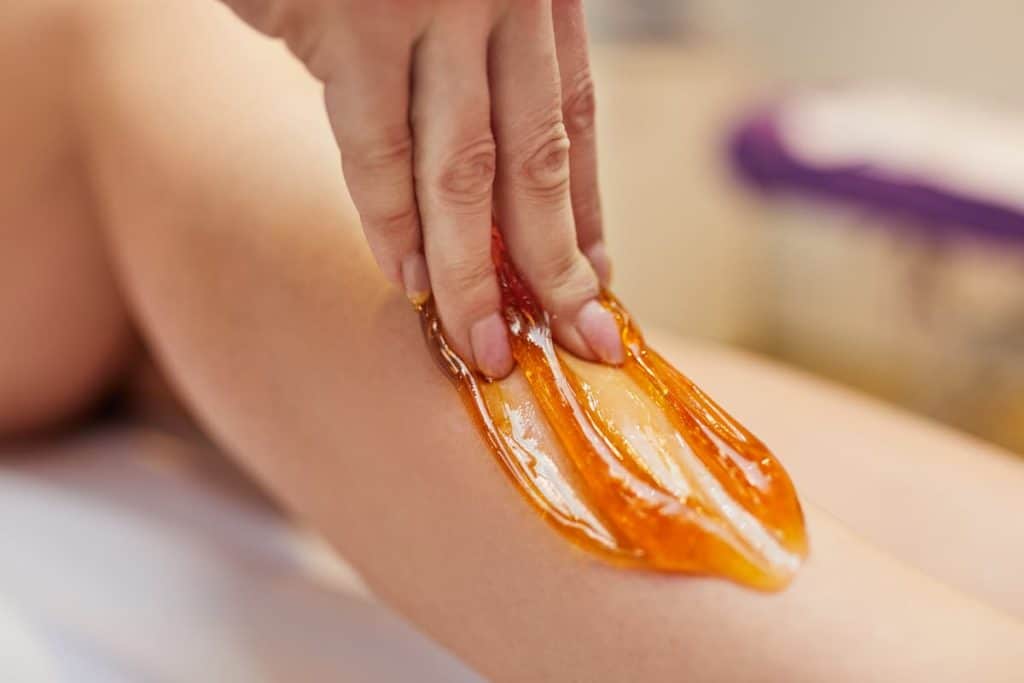 A specialist doing the waxing to one side of a woman's leg
