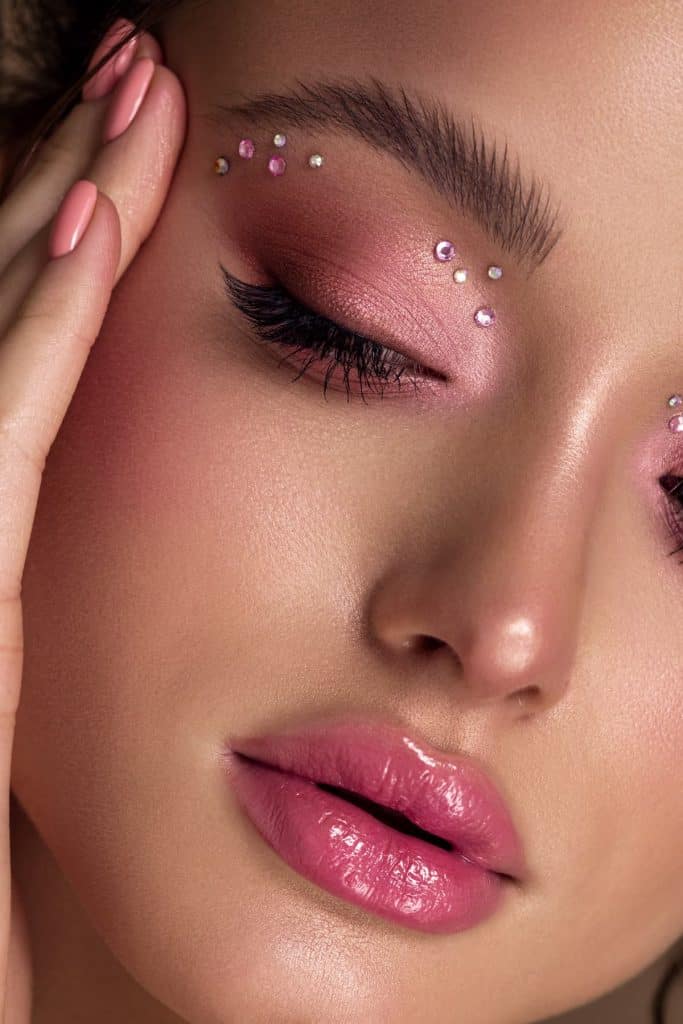 close up photo of a woman's monochromatic pink makeup with rhinestones on eyeshadow