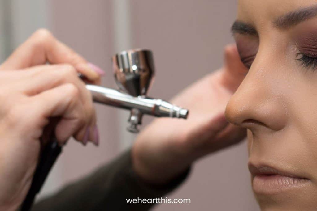 a make up artist applying airbrush foundation to her client