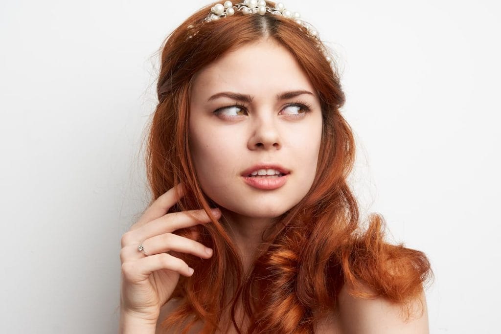 A beautiful light red haired woman wearing a wedding tiara on a white background