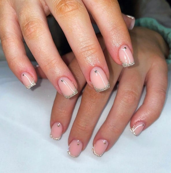 A woman's hand with silver glitter french tip nails