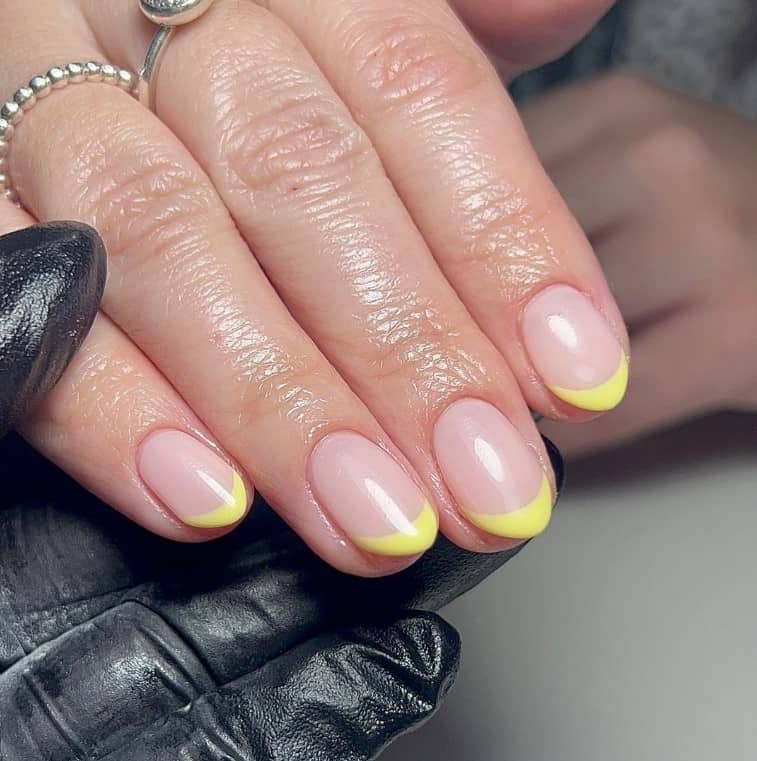 A woman's hand with short nails and yellow french tip nails