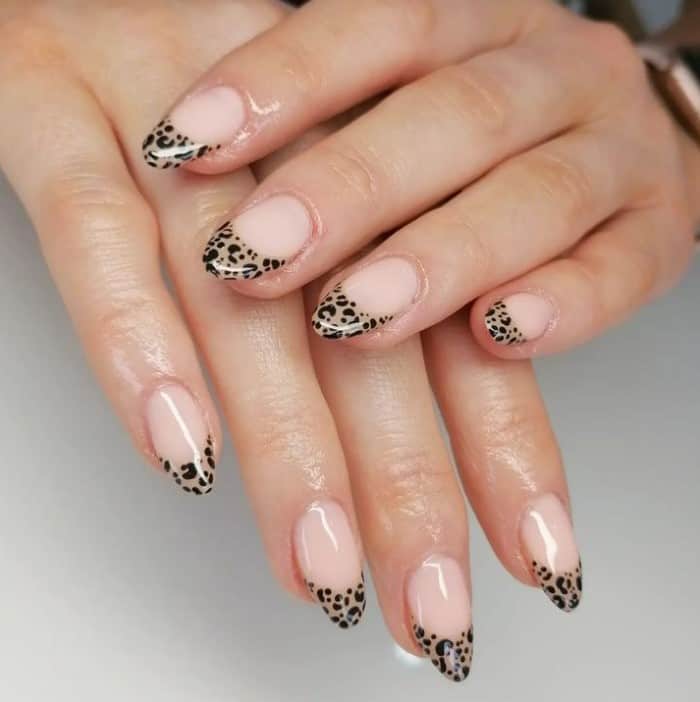 A closeup of a woman's hands with muted beige nail polish that has a leopard print