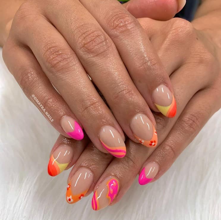 A woman's nails with bright orange and pink freehand curve designs on tips