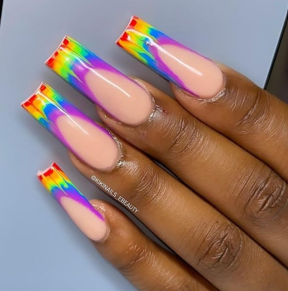 A woman's hand with rainbow tie-dye themed french tip nails