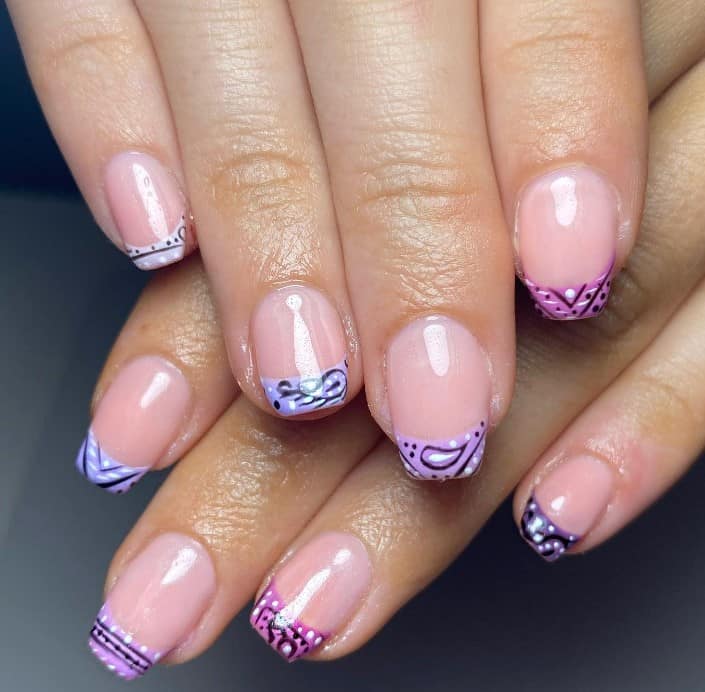 A woman's nails with purple and pink bandana designs on tips