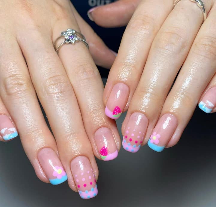 Short squoval nails with light blue and light pink tips decorated with clouds, dots, flowers, and berries