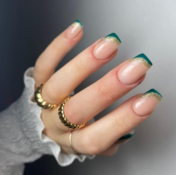 A woman's hand with green and gold french tip on square nails