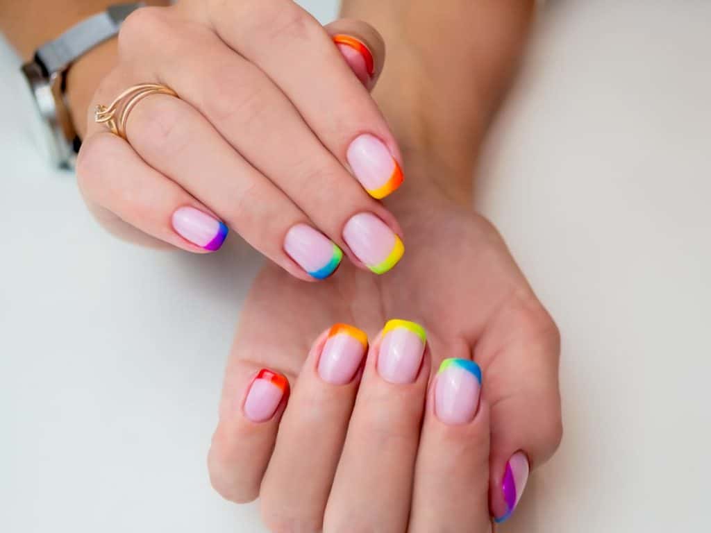 A woman's nails with multi-colored rainbow ombre french tip design