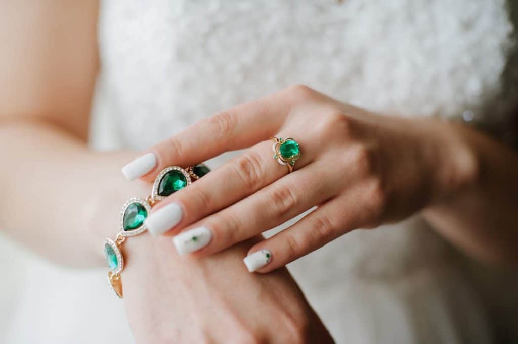 Emerald ring and bracelet on a bride's hand.