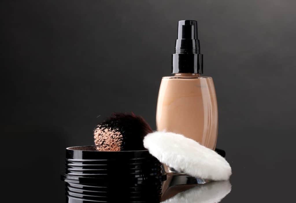 Foundation bottle with cotton and brush isolated on black