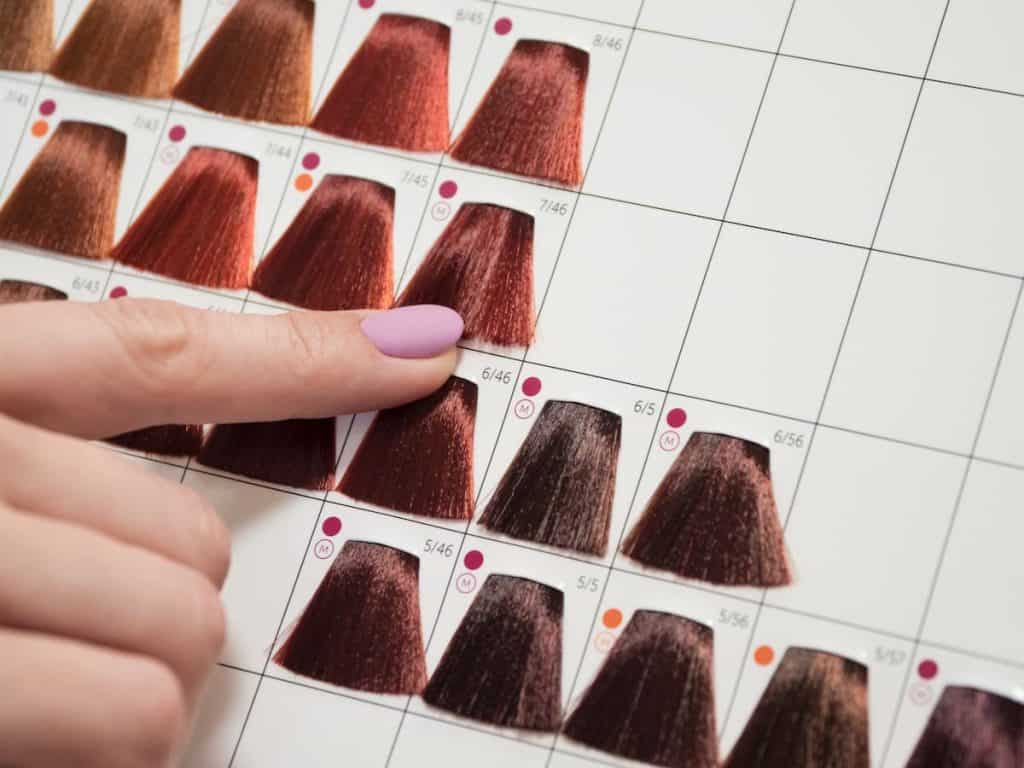 A woman's hand pointing at hair color number chart