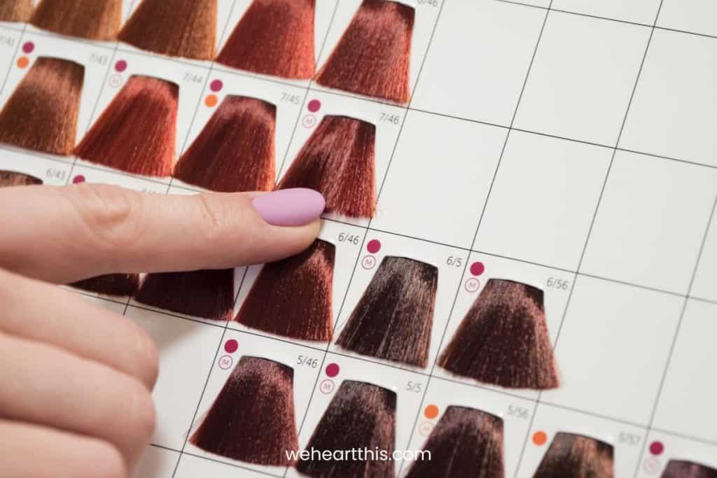 A hand pointing at hair color samples