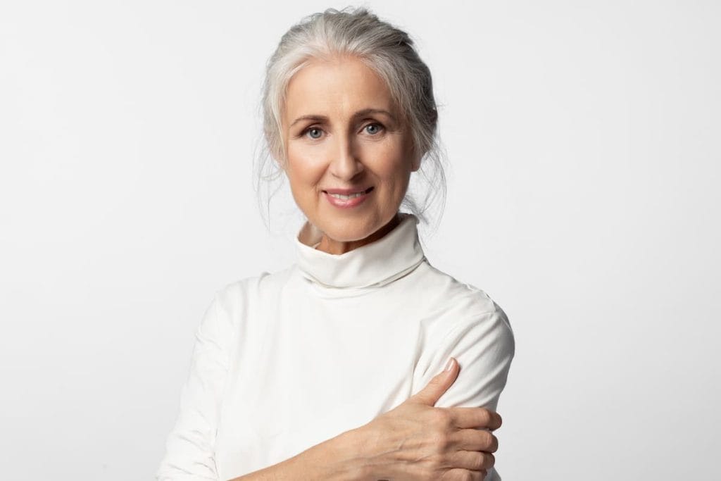 A woman with gray hair is posing on a white background.
