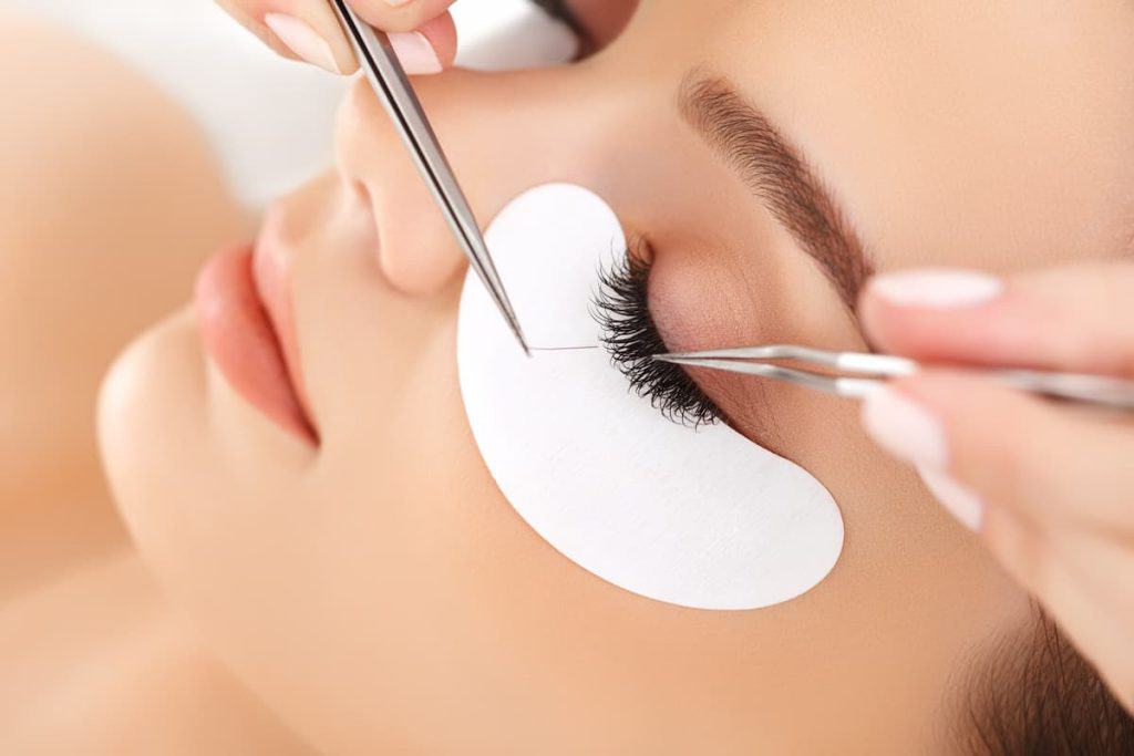 A lash artist applying lash extensions to the woman's eye