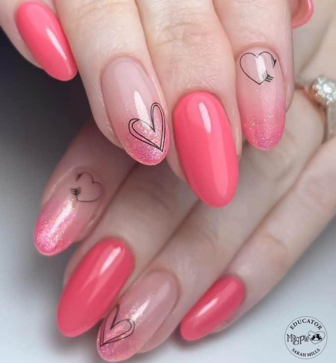 A closeup of a woman's hands with pale pink nail polish that has glitter and a few heart stickers on select nails