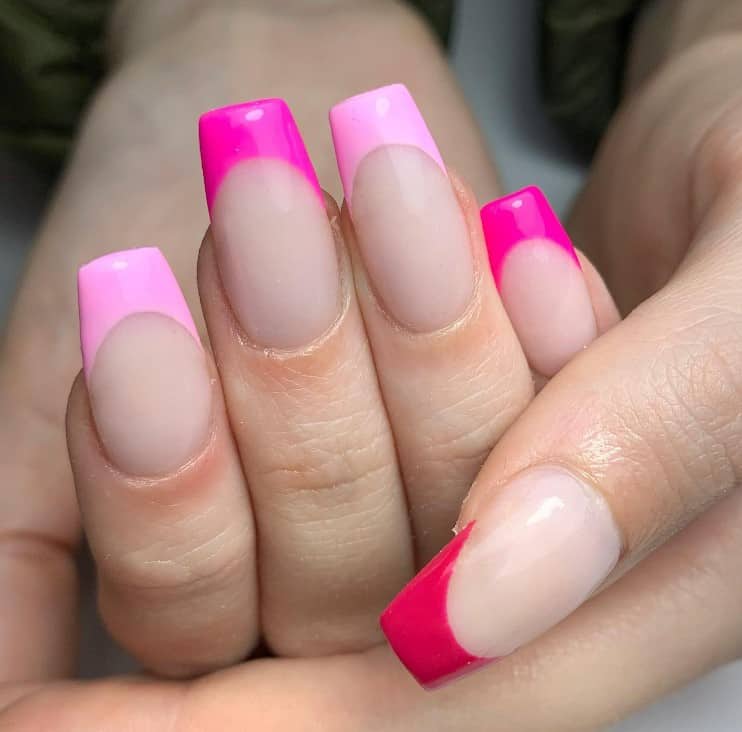 A closeup of a woman's hands with nude nail polish base that has different shades of pink on the tips