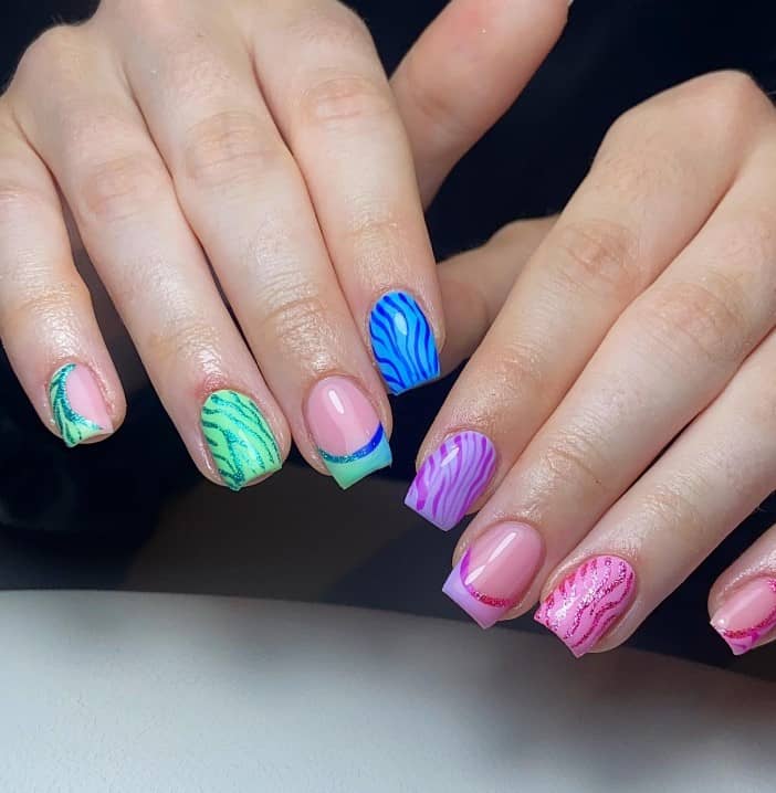 A closeup of a woman's hands with nude nail polish that has colorful zebra stripes in different patterns on pastel-colored short square nails