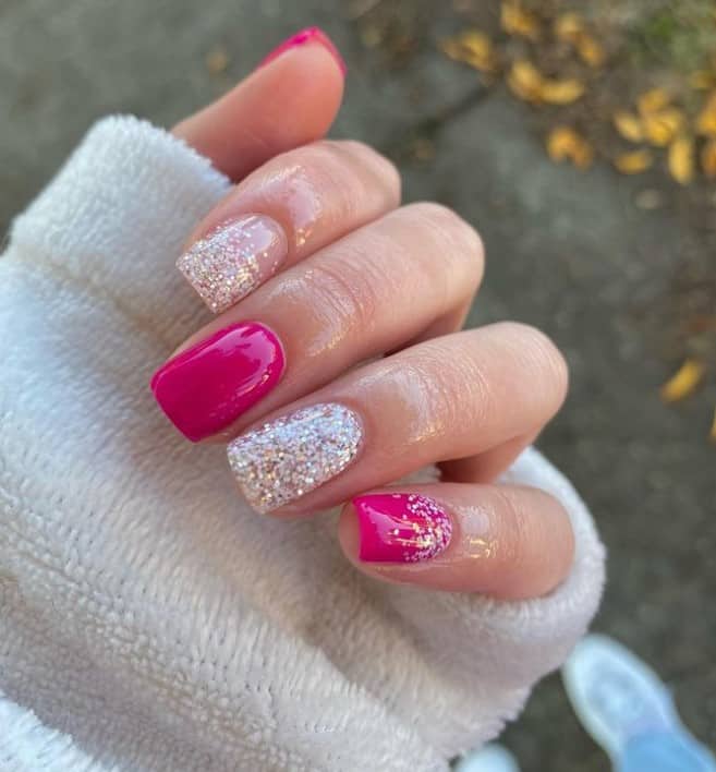 A closeup of a woman's hand with a combination of hot pink and glitter nail polish