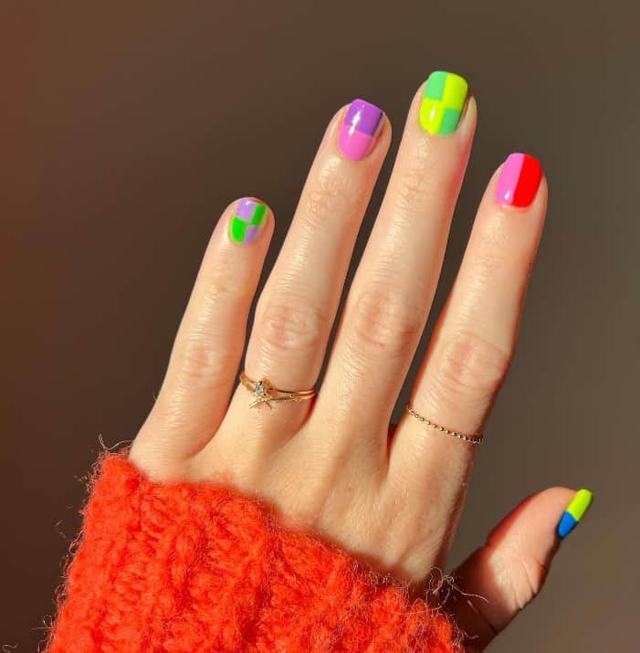 A closeup of a woman's hand with well-defined lines and geometric shapes with rich, vivid color combinations nail polish