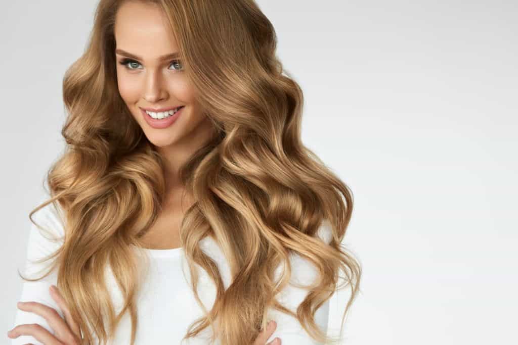 photo of smiling woman with beautifully styled long hair colored with hazelnut blonde