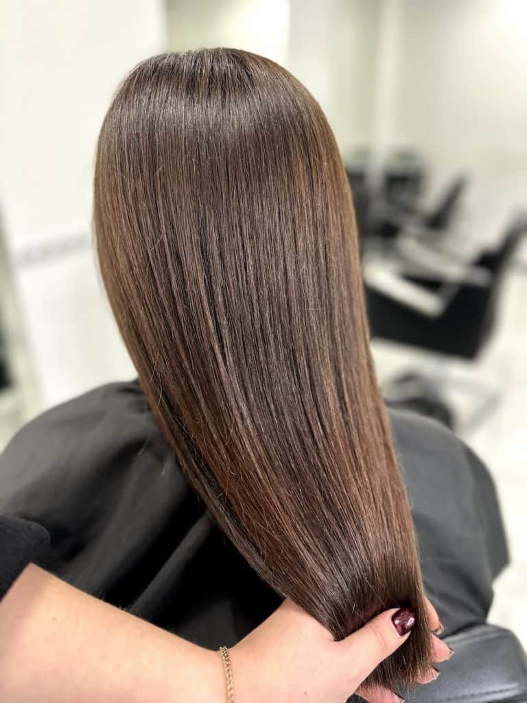 close up photo of woman's straight hair with hazelnut brown color