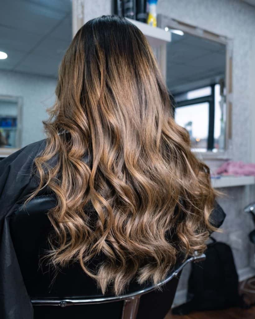 woman at the salon with her long hair colored hazelnut highlights