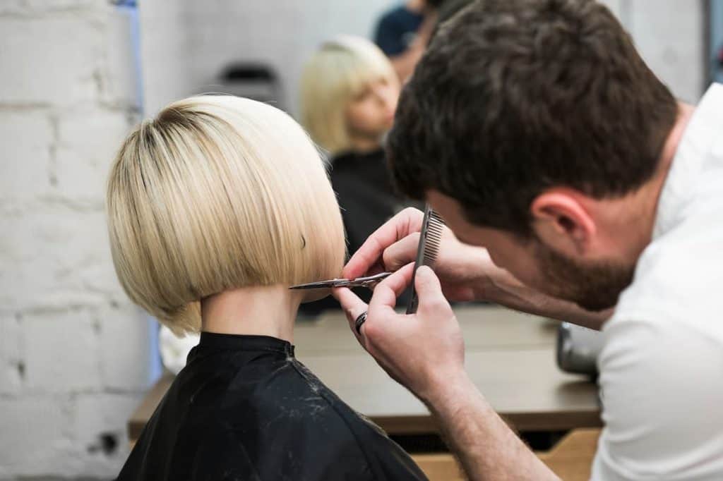 photo of a blonde short-haired woman at a salon having a blunt haircut
