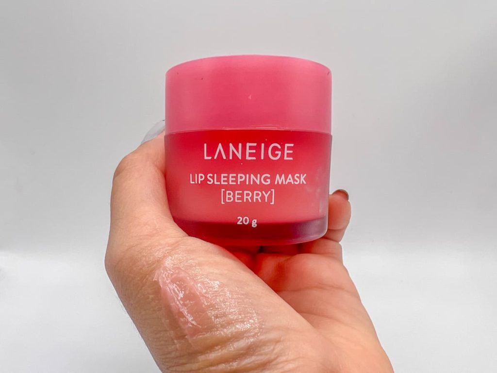 a woman's hand holding laneige lip sleeping mask with a product swatch on her hand 