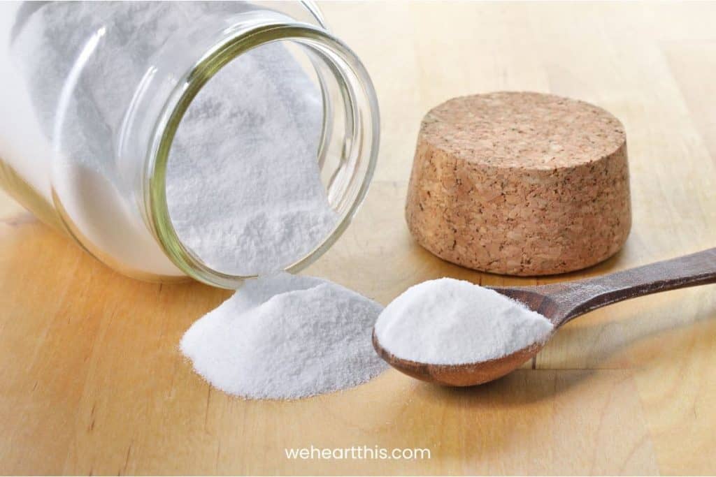 Close-up of baking soda in a glass jar and spoon isolated on a wooden background