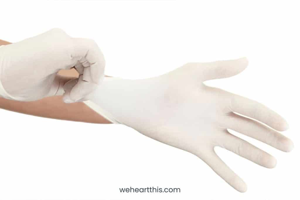 A specialist pulling on surgical glove isolated on a white background