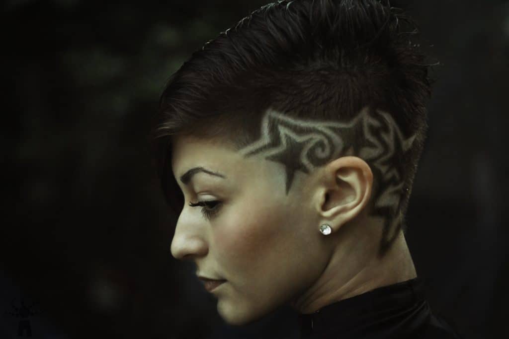 side view of a woman with a styled fade haircut on a dark background