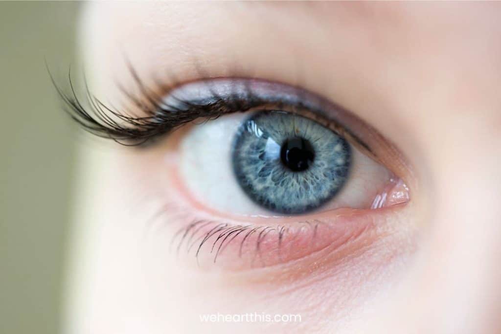 A closeup image of a woman's warm blue eye with longer eyelashes