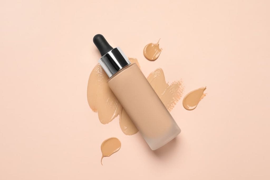 A bottle of oil-based foundation on a beige background.