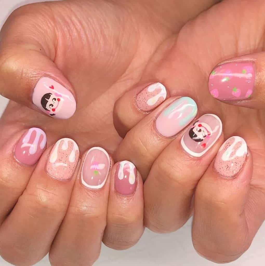 A closeup of a woman's hands with pink and peach nail polish that has gold glitter, a cute girl’s face, strawberries, and melting ice cream nail designs