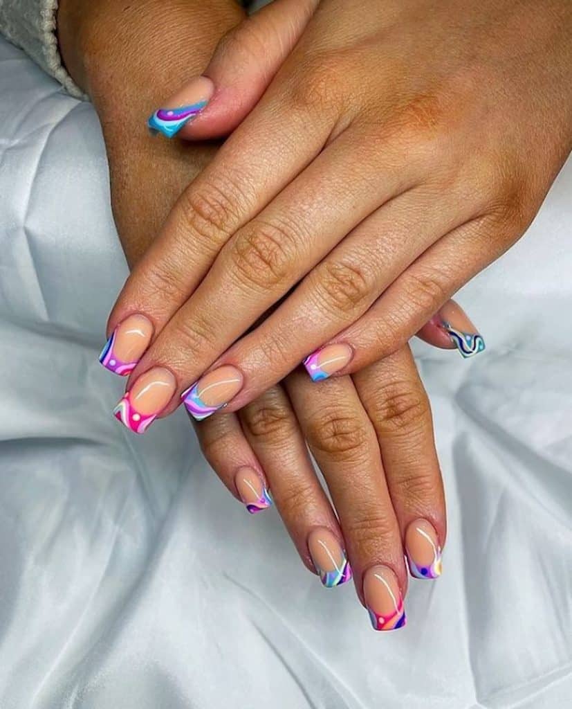 A woman's hands with nude nail polish base that has multicolored French tips in an abstract nail design