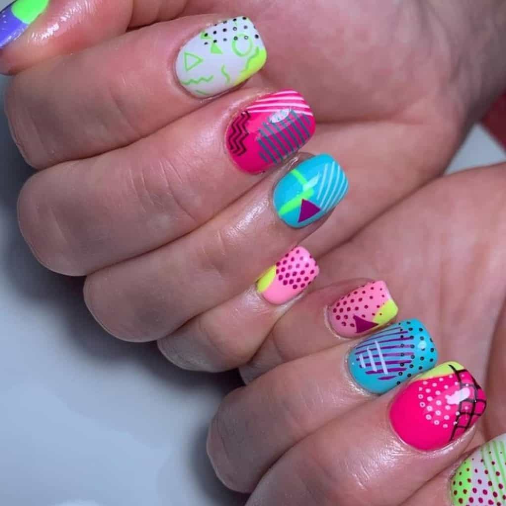 A closeup of a woman's hands with bright colored nails that has abstract designs and geometric art designs