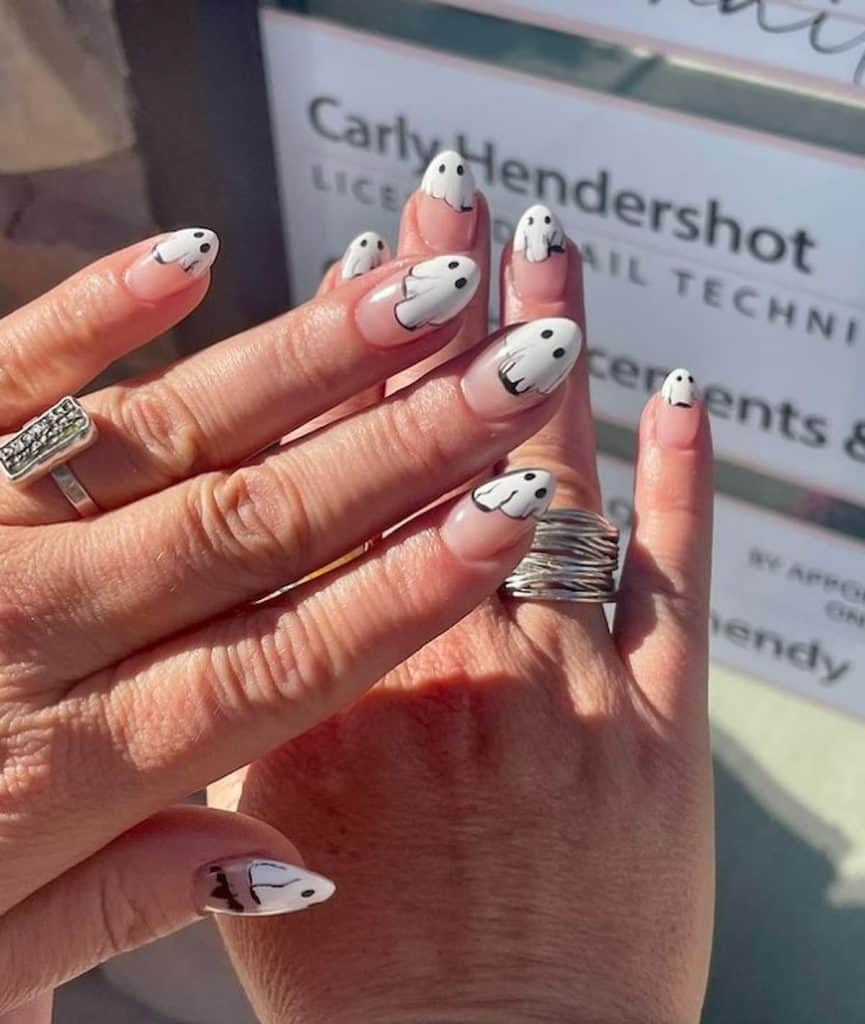 A woman's hands wearing a ring that has a hand-painted ghost nail design 
