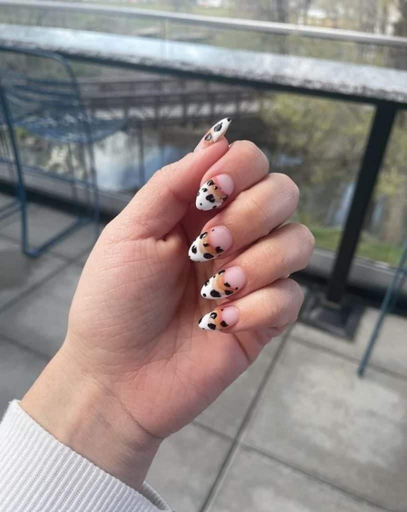 A woman's hand with a beautiful nude polish that has a cow print and faded brown lines nail design