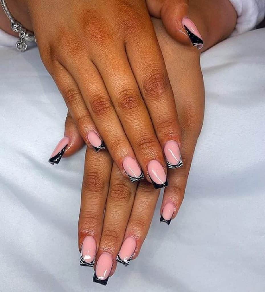 A woman's hands with a beautiful next extensions that has a rosy pink nail base with a black and white zebra pattern nail tips 