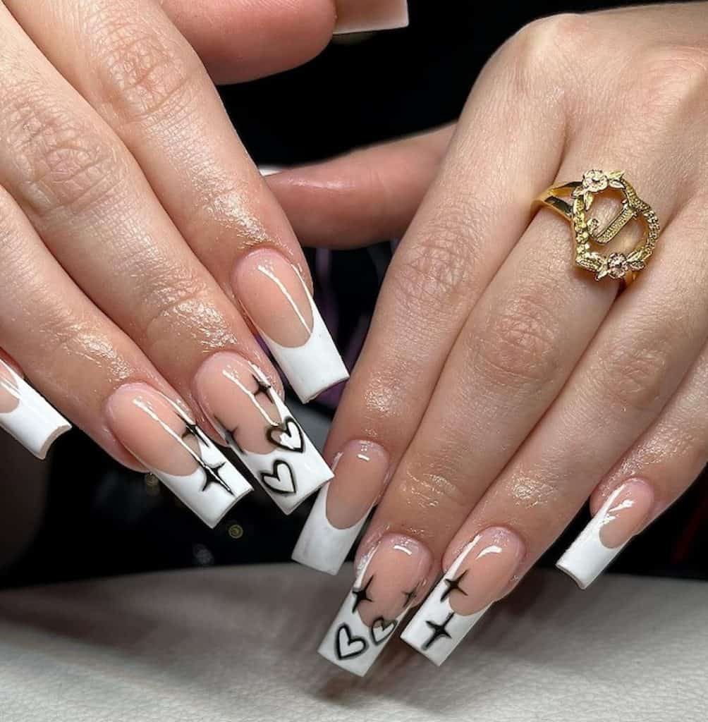 A woman's hands wearing a ring with a nude nail polish that has hearts and sparkles design on some of the nails 