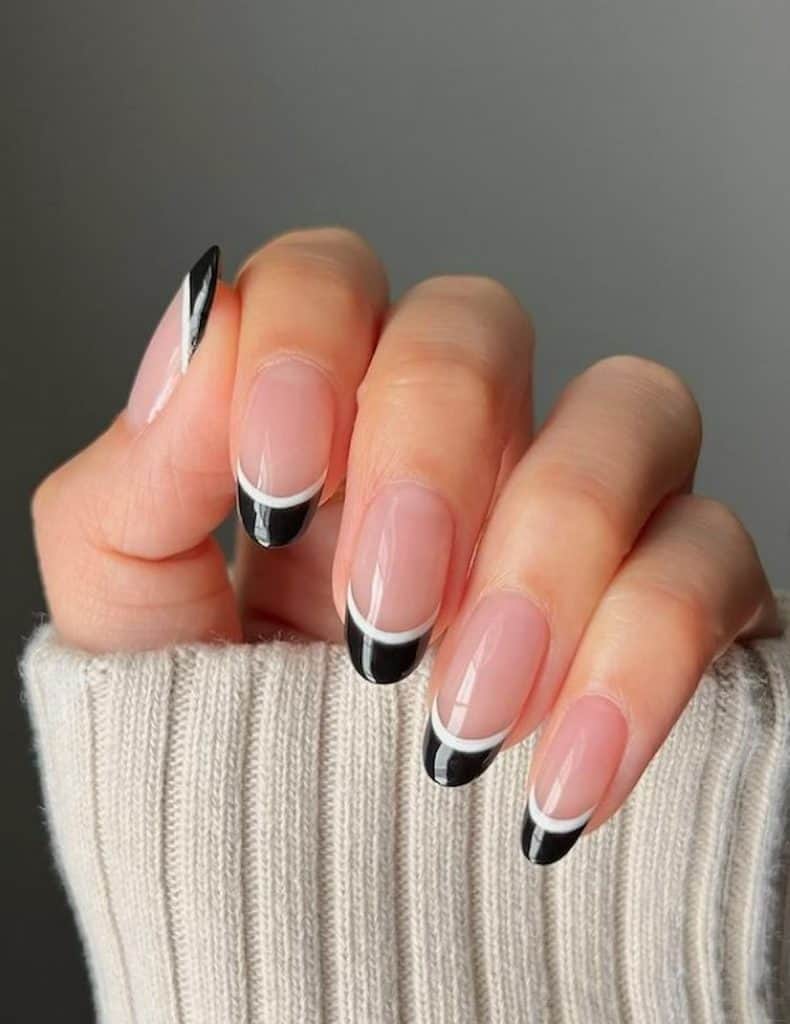 A woman's hand with beautiful nude nail polish that has double-lined black-and-white tips