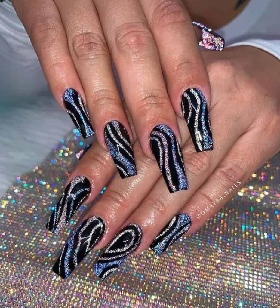 A woman's hands with a black nail polish that has swirly holographic lines and multicolored glitter