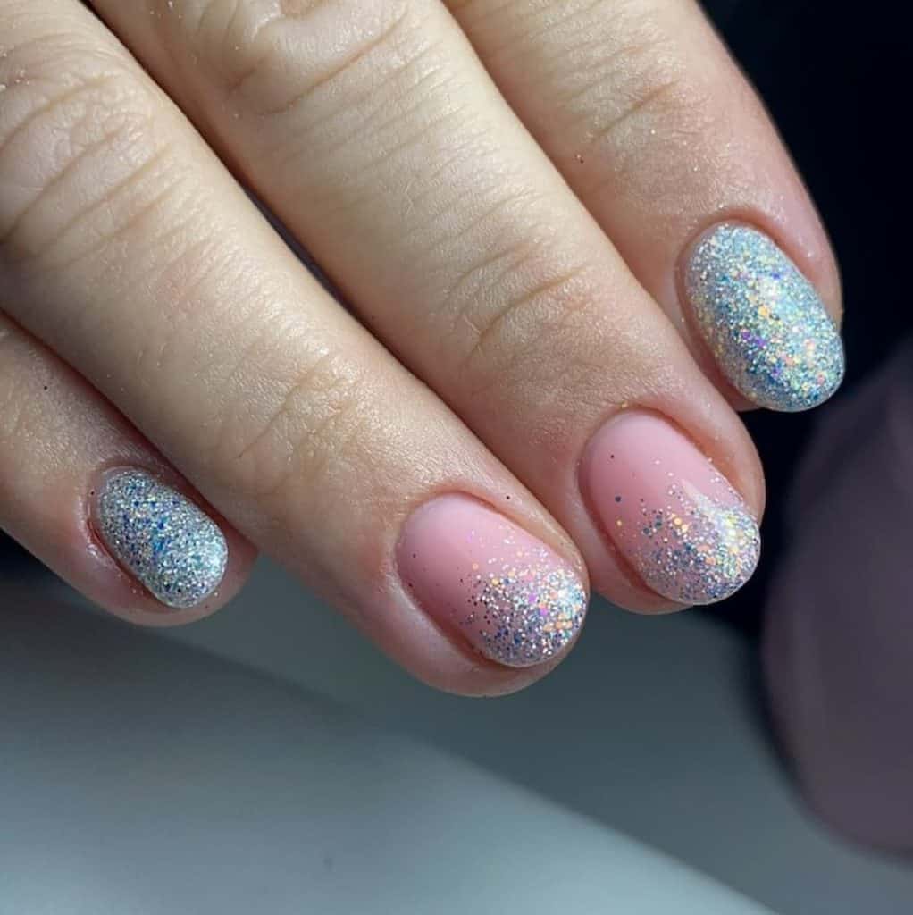 A closeup of a woman's hand with pink and baby blue nail polish that has glitters